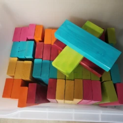 A container of colorful wooden blocks in shades of pink, blue, yellow, orange, and green, arranged in a random order.