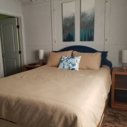 Bedroom with a double bed, beige bedding, two bedside tables with lamps, and abstract art above the headboard.