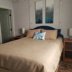 Bedroom with a double bed, beige bedding, two bedside tables with lamps, and abstract art above the headboard.
