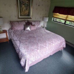 A bedroom with a large bed covered in pink floral bedding, decorative pillows, two side tables with lamps, and a bicycle-themed artwork.