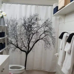 Bathroom with a tree-themed shower curtain, white vanity, and shelves with towels and decor items.